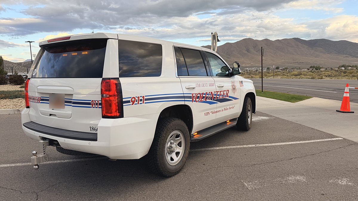 EMVIPS volunteer Tahoe marked Utah County Sheriff Volunteer, rear view with mountains.